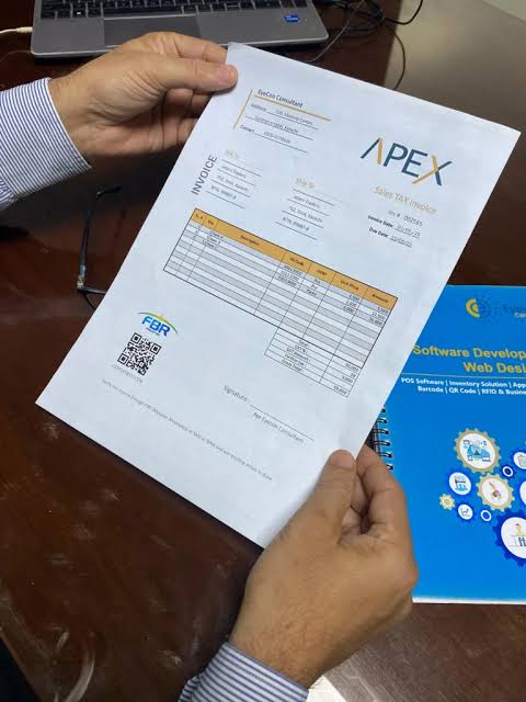 Sample sales tax invoice with FBR logo and QR code held for verification